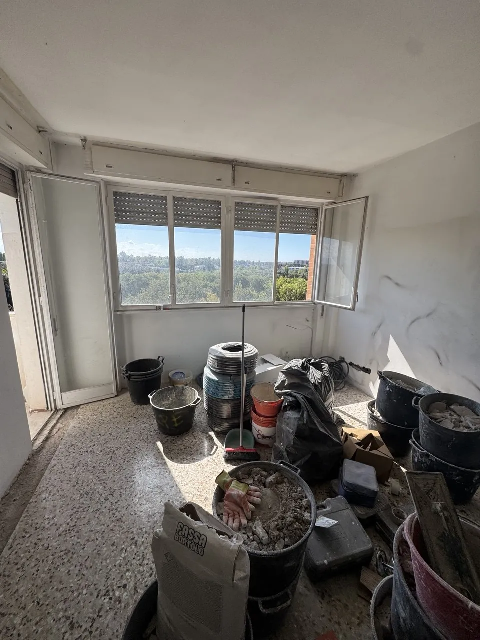 Stanza in ristrutturazione con materiali e attrezzi, vista sulla finestra